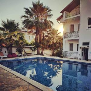 a swimming pool in front of a building with palm trees at Garden-view suite room in Ortaca