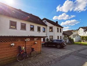 a house with a car parked in a driveway at Pension am Kirchberg - Zimmer 2 in Daun