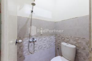 a bathroom with a shower and a toilet at Nipa Guest House near Universitas Widyagama Mitra RedDoorz in Blimbing