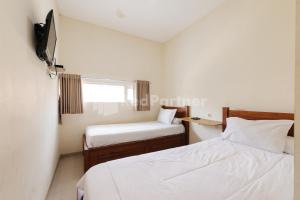 a small bedroom with two beds and a window at Nipa Guest House near Universitas Widyagama Mitra RedDoorz in Blimbing