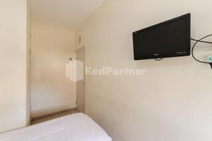 a room with a tv on a white wall at Nipa Guest House near Universitas Widyagama Mitra RedDoorz in Blimbing +19 photos