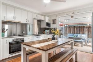 a kitchen with white cabinets and a wooden table at 1-41 Park Street in Evans Head