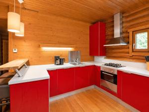 a kitchen with red cabinets and wooden walls at Rustic chalet near SkiWelt Wilder Kaiser in Salvenberg
