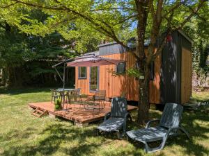 a cabin with a table and chairs and an umbrella at Tiny house in Saint-Côme-dʼOlt