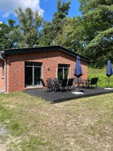a patio with chairs and umbrellas in front of a building at Am Grasengrundsberg in Soltau