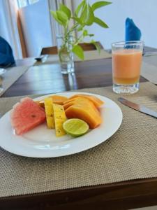 a plate of fruit on a table with a glass of juice at Esmin's Homestay - Women Only in Hatton