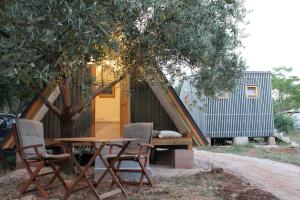 a table and chairs under a tree with a house at Bungalov B in Sveti Filip i Jakov +6 photos