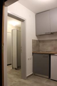an empty kitchen with white cabinets and a doorway at Bungalov B in Sveti Filip i Jakov