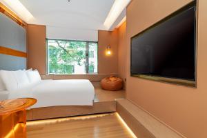 a bedroom with a bed and a large flat screen tv at Yee Hotel Shamian Guangzhou in Guangzhou