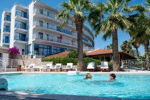 a man and woman swimming in a swimming pool next to a hotel at HOTEL SISSY in Kamena Vourla