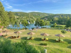 a group of chairs and umbrellas on a field next to a river at Villa Canyon Escape 12 Personen in Bilišane