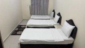 two beds in a room with white sheets at هدى صلالة in Salalah