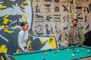 a man and woman standing next to a pool table at Hidden Cabin in Iringa