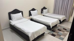 a room with three beds with white sheets at هدى صلالة in Salalah
