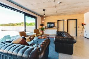 a living room with leather furniture and large windows at Daft Hotel & Glamping in Malmedy