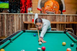 a woman is playing pool with a cue at Hidden Cabin in Iringa +12 photos
