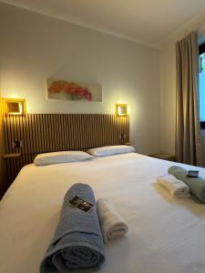 a bedroom with a large white bed with towels on it at Frenk house over Varenna in Perledo