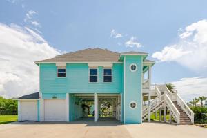 a blue house with a white garage at 3 King Suites 15 Guests - Sunzout in Bolivar Peninsula