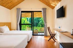a hotel room with two beds and a sliding glass door at An Binh Village in Yên Bình