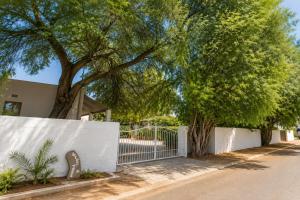 a white fence with a tree in front of a house at Cedar Stay Clanwilliam in Clanwilliam