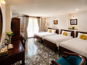 a hotel room with two beds and a table at Hanoi Luxury Hotel - Old Quarter in Hanoi