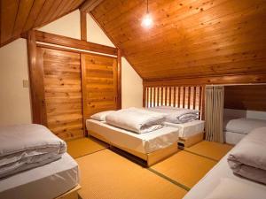 two beds in a room with wooden ceilings at Maruta ひたち大宮 in Takabu +14 photos