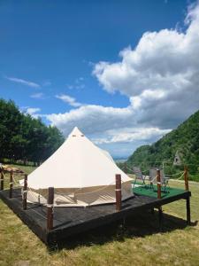 a white tent in a field with two chairs at Camping Inima Retezatului in Nucşoara