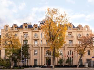 a large beige building with a sign on it at Baden-Baden Hotel Tashkent in Tashkent
