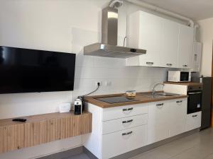 a kitchen with white cabinets and a flat screen tv at Suite Terrazza Mazzini in Molinella +5 photos