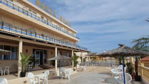 a hotel with chairs and umbrellas in front of it at Hotel Bahía by ALEGRIA in Puerto de Mazarrón