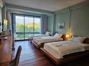 a hotel room with two beds and a window at Piney Stay ไพนี่สเตย์ เขาค้อ in Campson