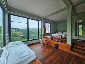 a bedroom with two beds and a desk and a large window at Piney Stay ไพนี่สเตย์ เขาค้อ in Campson
