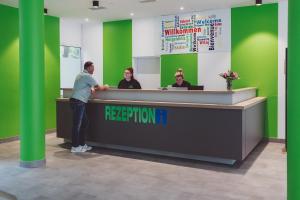 a man standing at a reception desk at Hotel City Green Hoppegarten in Hoppegarten