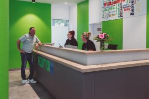 a man standing at a cashier counter in an office at Hotel City Green Hoppegarten in Hoppegarten +19 photos