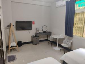 a room with a tv and a desk and a table at Kinmen Huan Bei 88 B&B in Jincheng