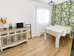 a dining room with a white table and a tv at La Villa des Demoiselles in Bourg-Achard