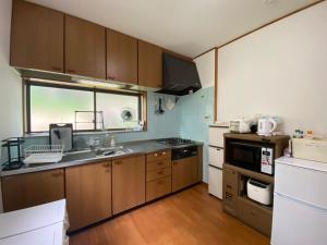 a kitchen with wooden cabinets and a sink and a stove at Guest House TETSU in Oshima