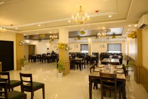 a restaurant with tables and chairs and a chandelier at Hotel Grand Mayfair in Dimapur