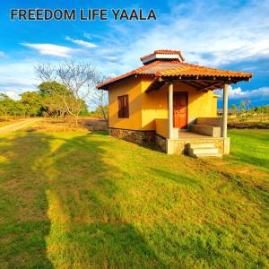 a small yellow house on a grassy field at Freedom Life Yala in Tissamaharama