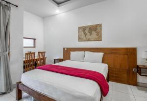 a bedroom with a large bed with a red blanket at Saren Guesthouse Bali in Kerobokan