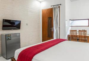 a bedroom with a bed with a red blanket on it at Saren Guesthouse Bali in Kerobokan