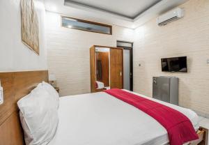 a bedroom with a white bed with a red blanket at Saren Guesthouse Bali in Kerobokan