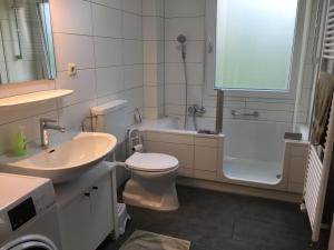 a bathroom with a sink and a toilet and a tub at Ferienhaus Bibernest in Münsingen +6 photos