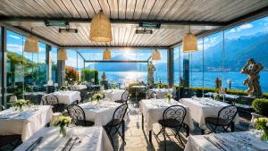 a restaurant with tables and chairs with a view of the mountains at Hotel Meridiana in Bellano +107 photos