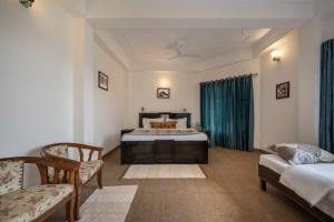 a bedroom with a bed and two chairs in it at Villa Harrington in Barog