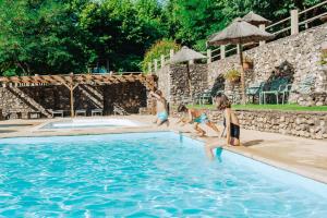 three girls are sitting in a swimming pool at Camping la Clémentine in Cendras