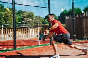 a man hitting a tennis ball on a tennis court at Camping la Clémentine in Cendras