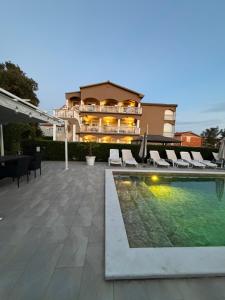 a swimming pool with chairs and a building at Apartmani Anđelo, Tommy, Leon in Bibinje
