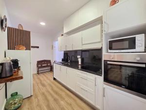 a kitchen with white cabinets and a microwave at Cantinho da Muralha in Melgaço