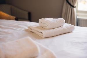 two towels are stacked on top of a bed at Oak House Hotel in Axbridge